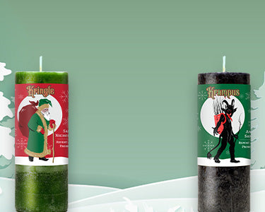 Coventry Creations Green Kringle Candle and Black Krampus Candle with Christmas trees and snowy hills in background