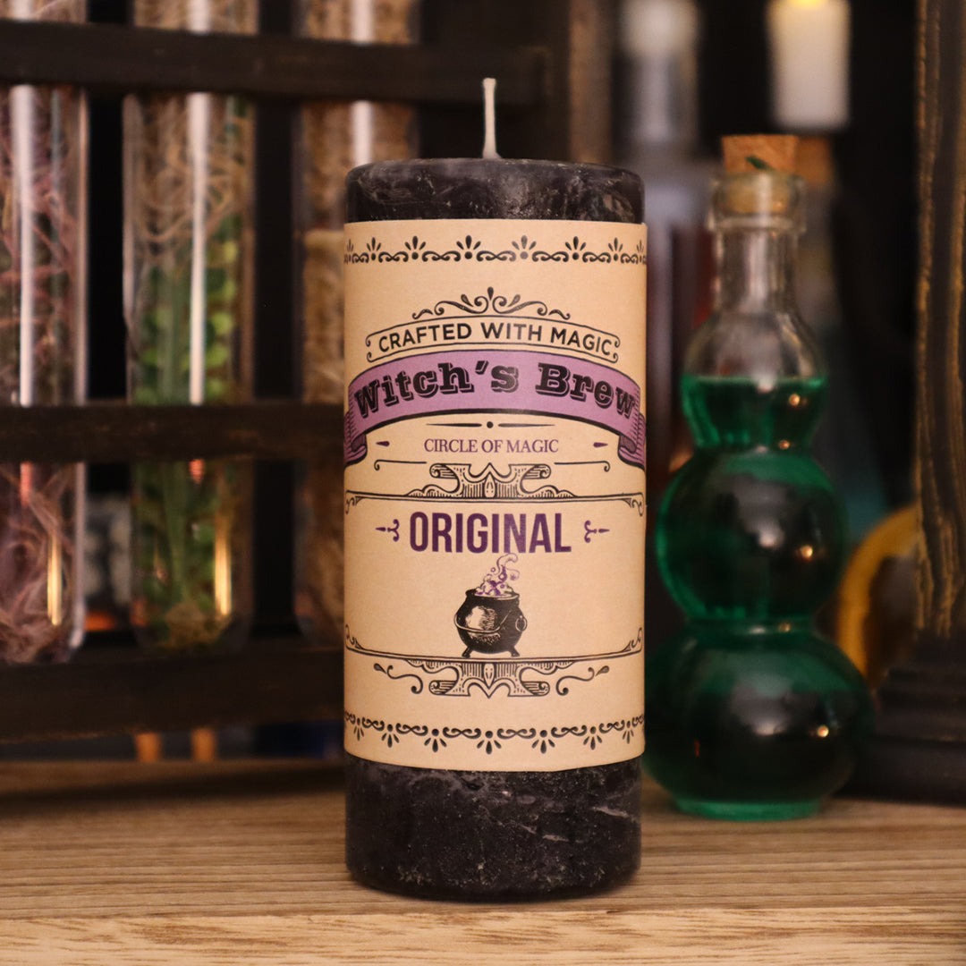 Coventry Creations Witch’s Brew Original Black Candle with potion bottles behind