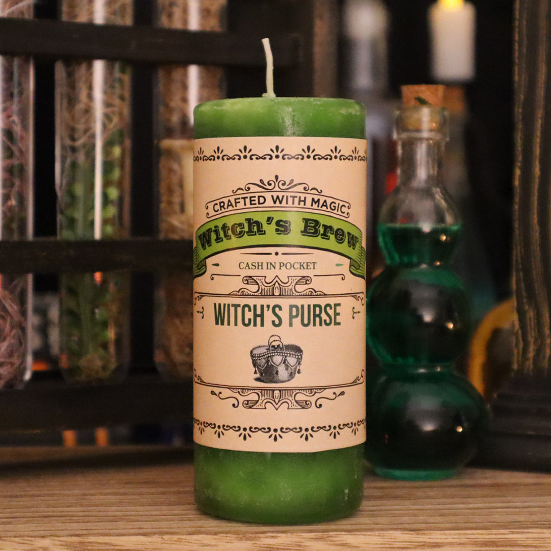 Coventry Creations Witch’s Brew Witch’s Purse Prosperous Green Candle with potion bottles behind